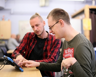 Zwei Personen bedienen ein Tablet. Ein Tablet ist ein digitales Endgerät. 